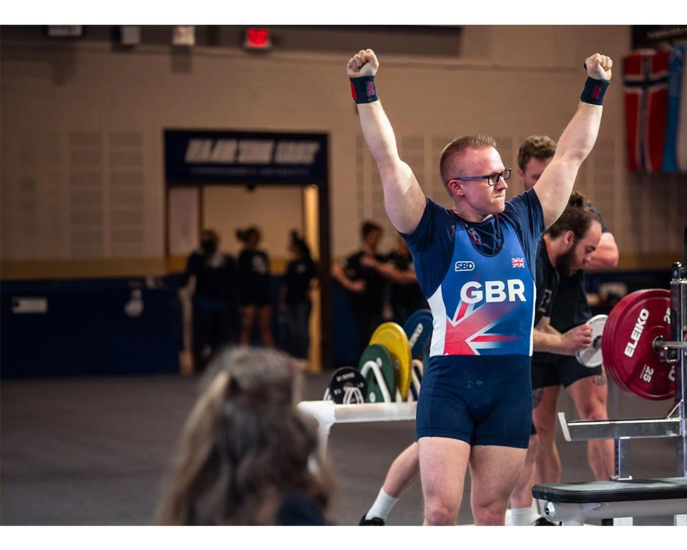 Andrew in the Great Britain singlet with both fists raised, celebrating his 175 kg personal best at the 2024 World Bench Press Championships
