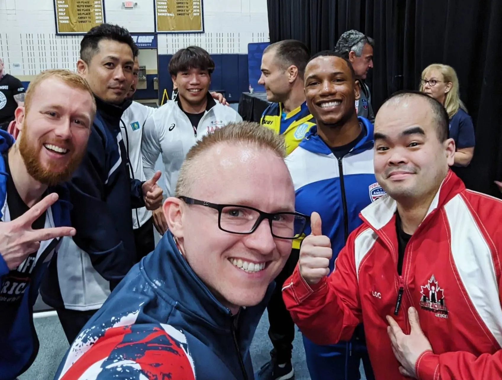 Selfie of Andrew with other lifters from the 74 kg class at the 2024 World Bench Press Championships in Austin, Texas, several giving thumbs up or peace signs